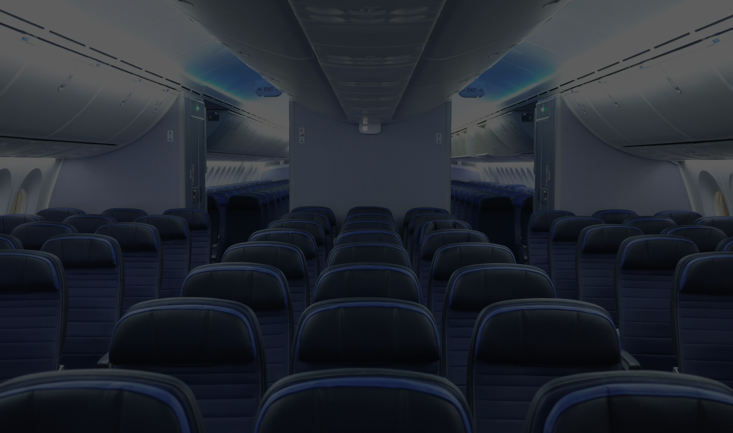 Interior of an airplane cabin showing rows of dark blue seats and overhead compartments